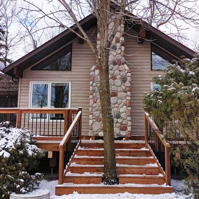 An interesting picture of a set of stairs built around a tree near a house.